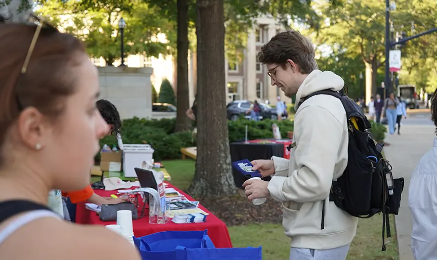 Student receiving swag from table on Quad